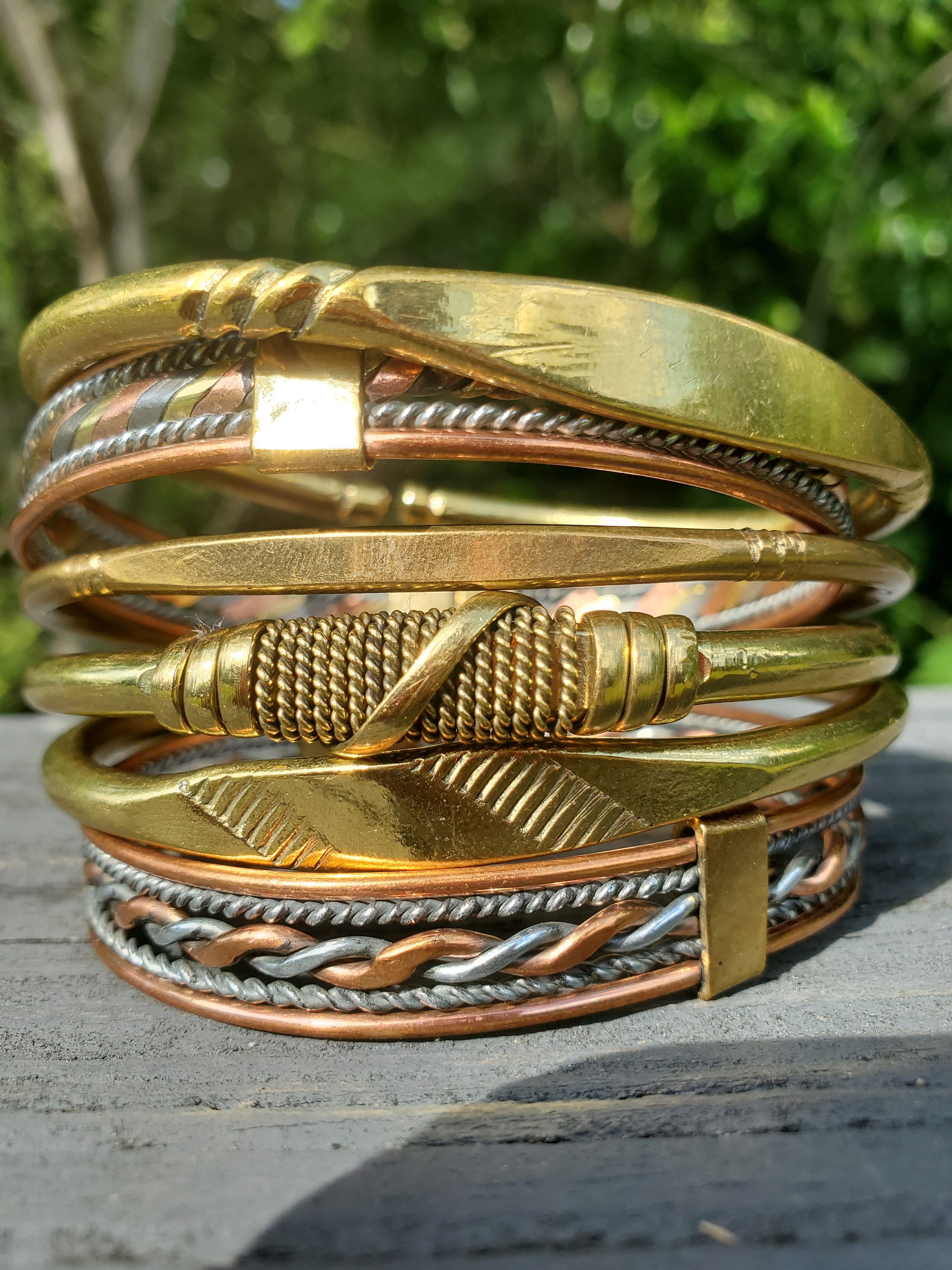 A stack of beautiful handmade brass, copper and aluminum bracelets.