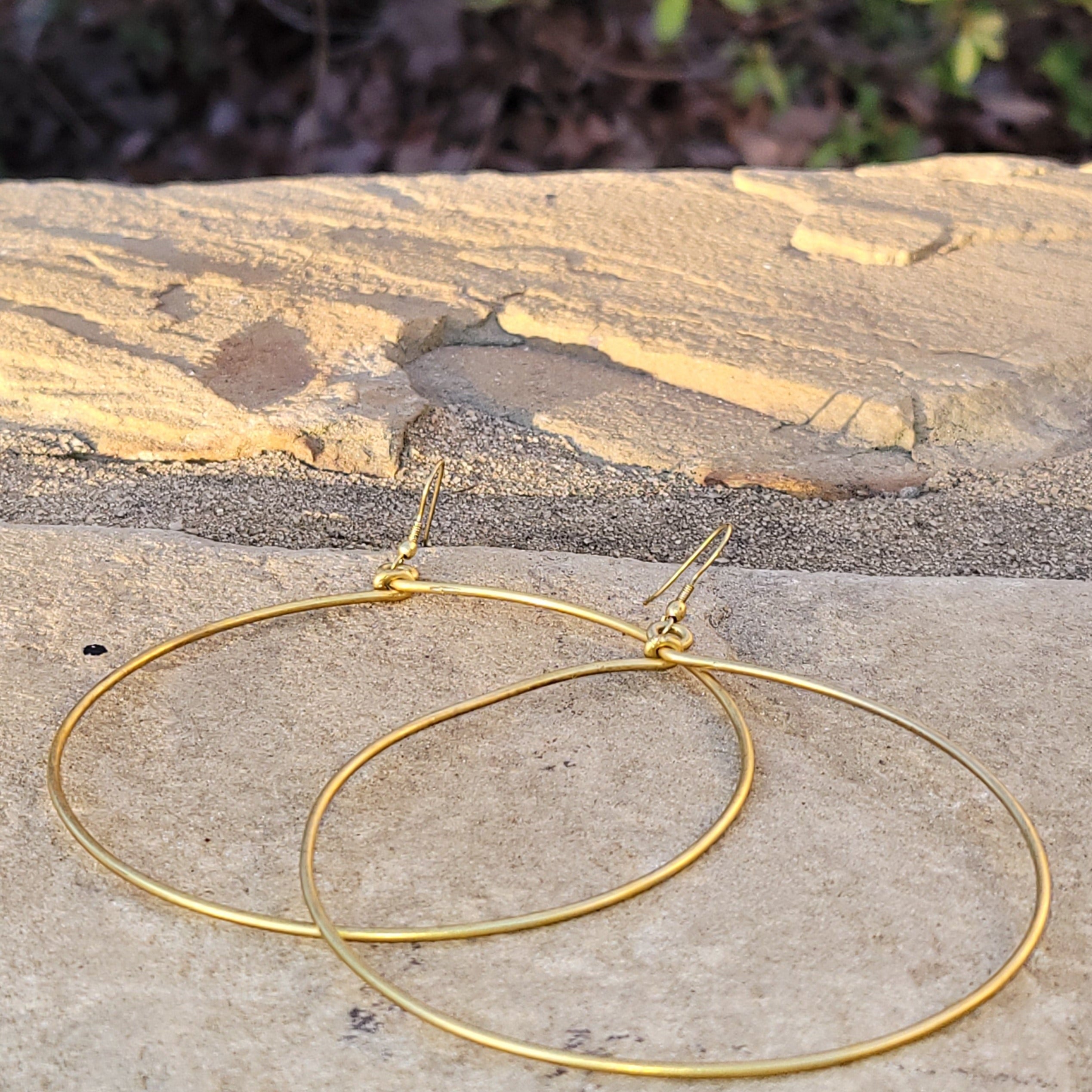 An image of gold-color Dramatic, wide-diameter statement brass hoops. Shop Kamawe