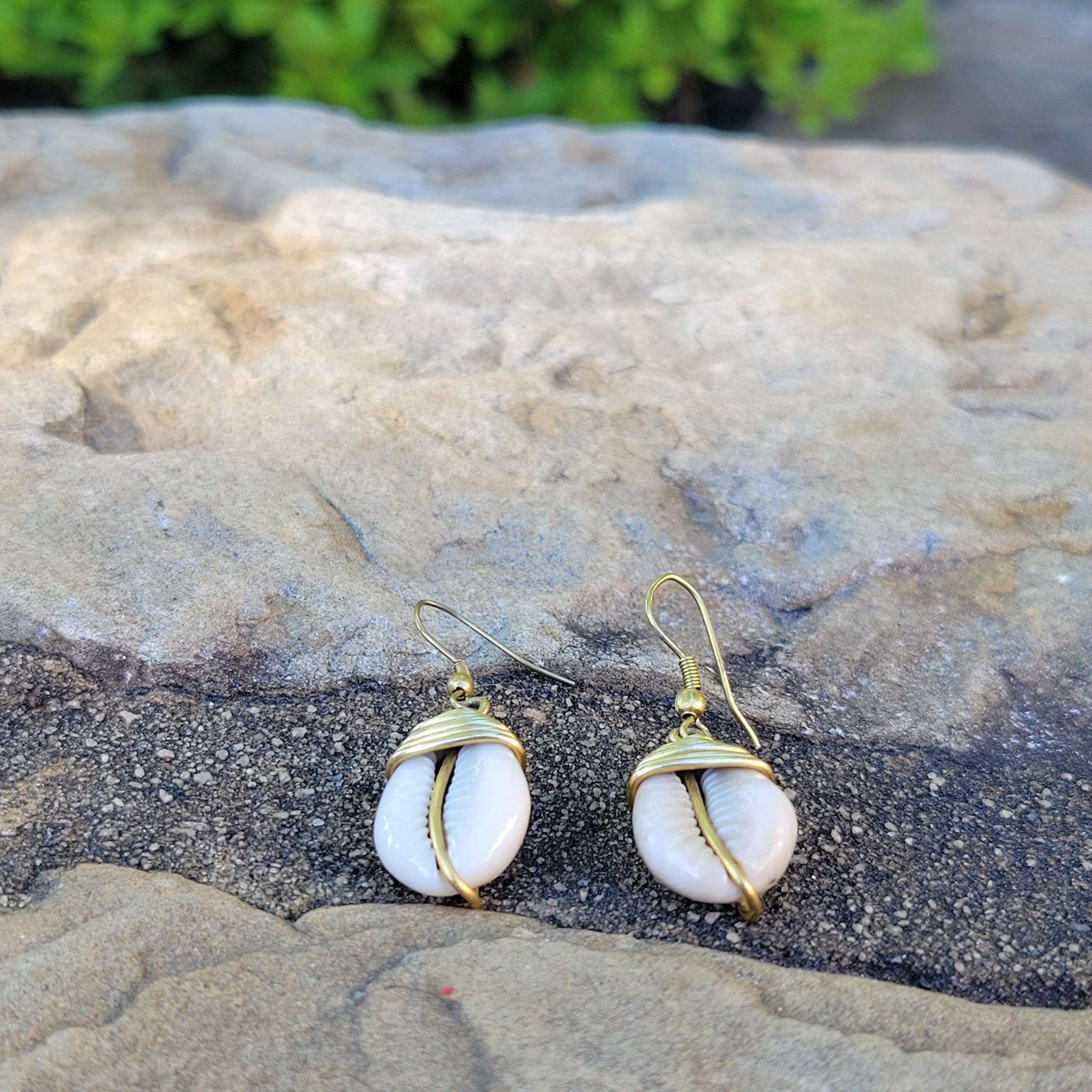 An image of gold & beige-color Simple brass drop finished with one cowrie. Shop Kamawe