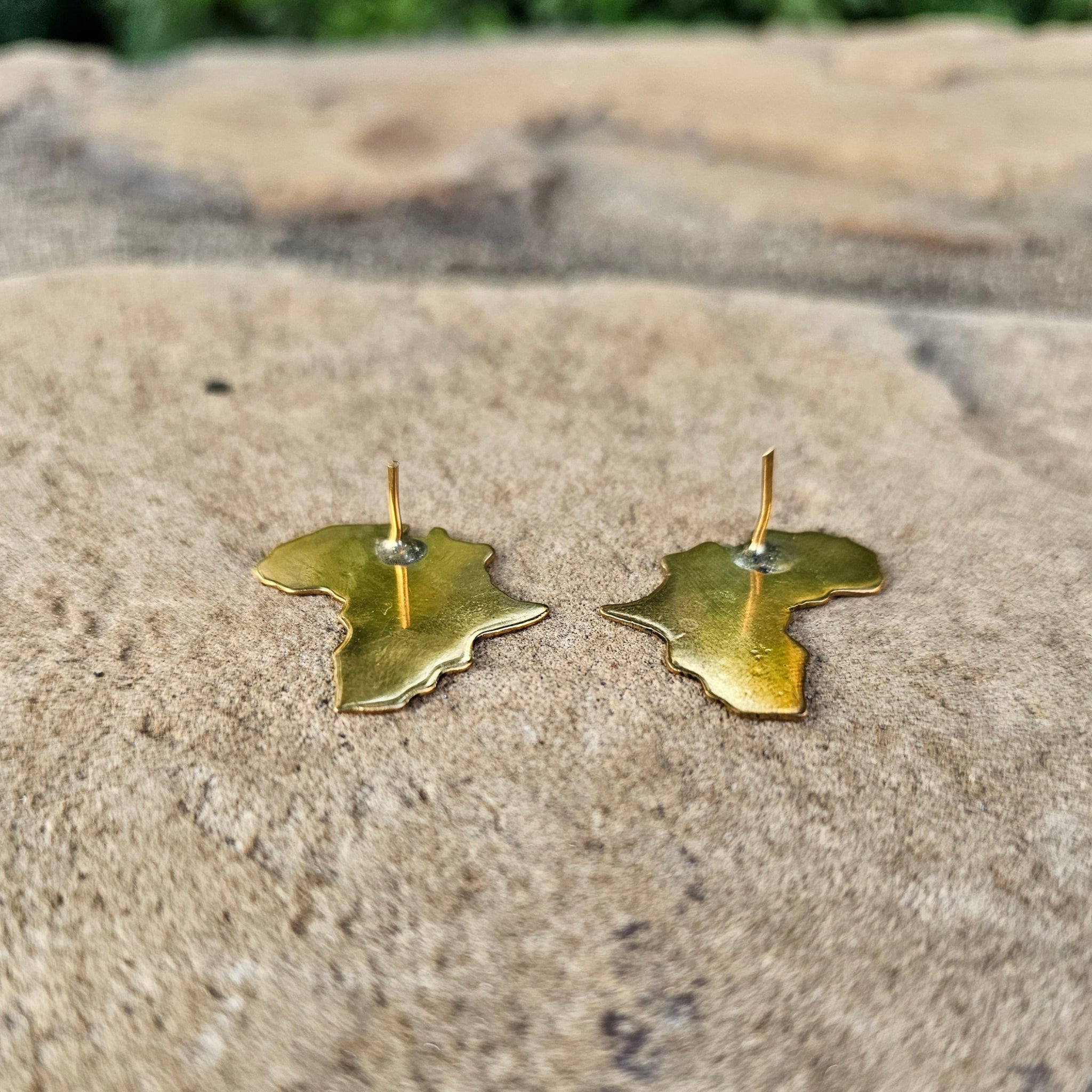 An image of gold-color Minimal Motherland-map studs in polished brass. Shop Kamawe
