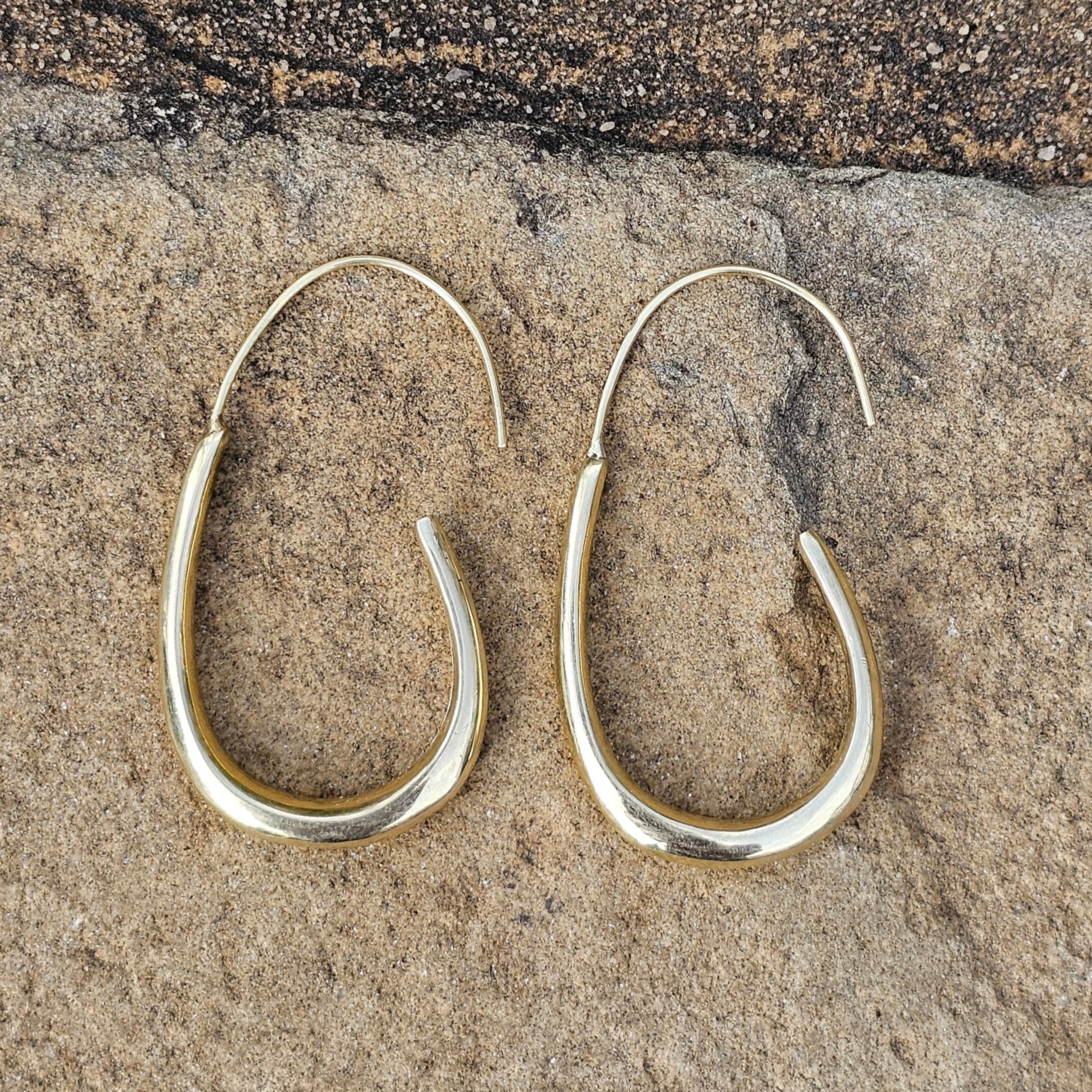 An image of gold-color One unbroken flowing brass line that arcs gently downward. Shop Kamawe