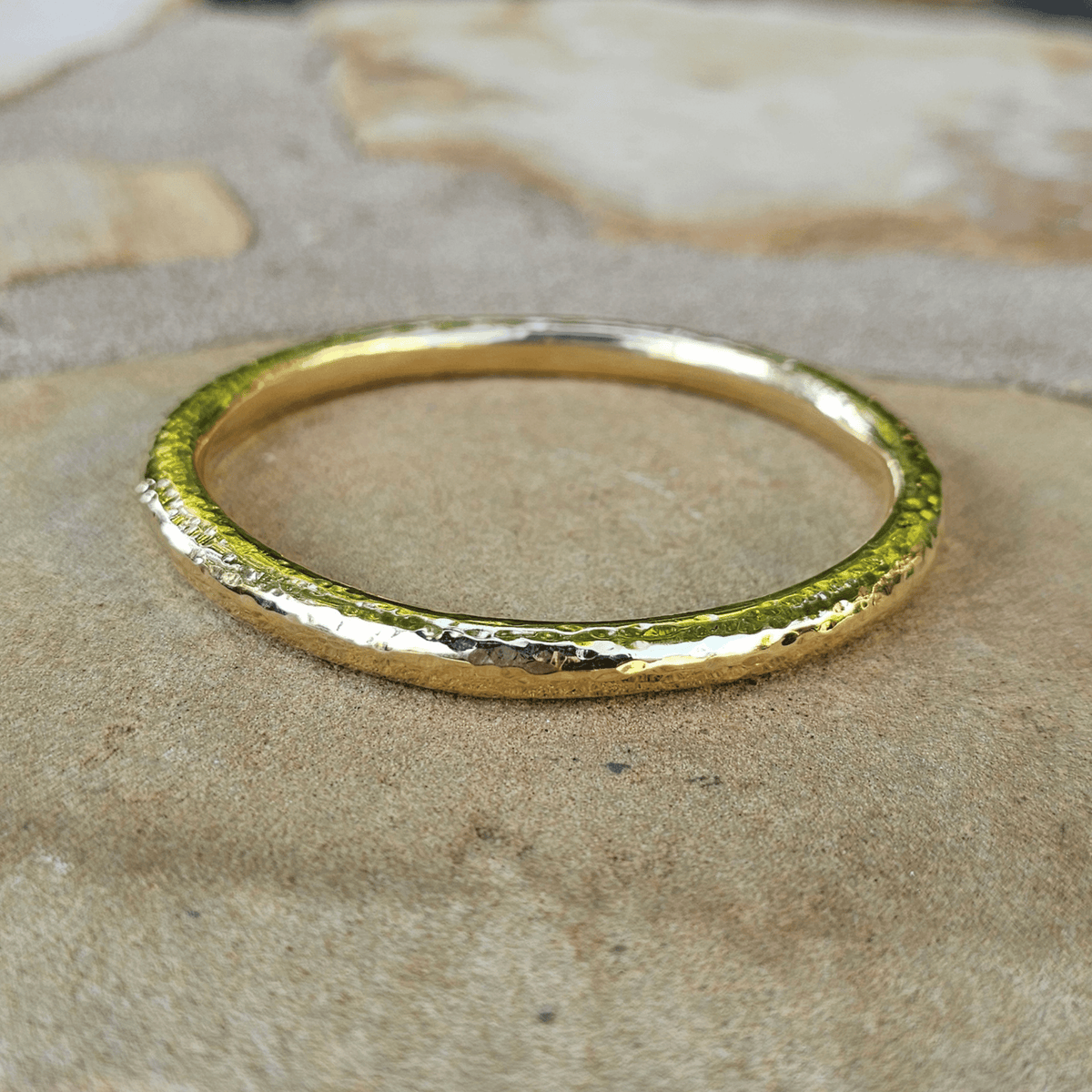 Hammered Brass gold ring on a stone surface. Shop Kamawe