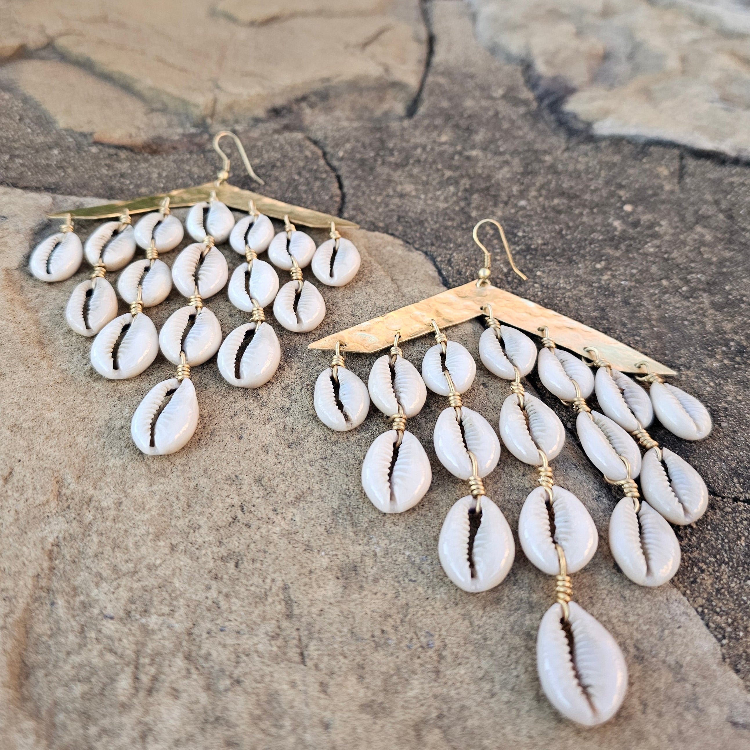 An image of gold & beige-color Layered hammered brass bars with cascading cowrie. Shop Kamawe