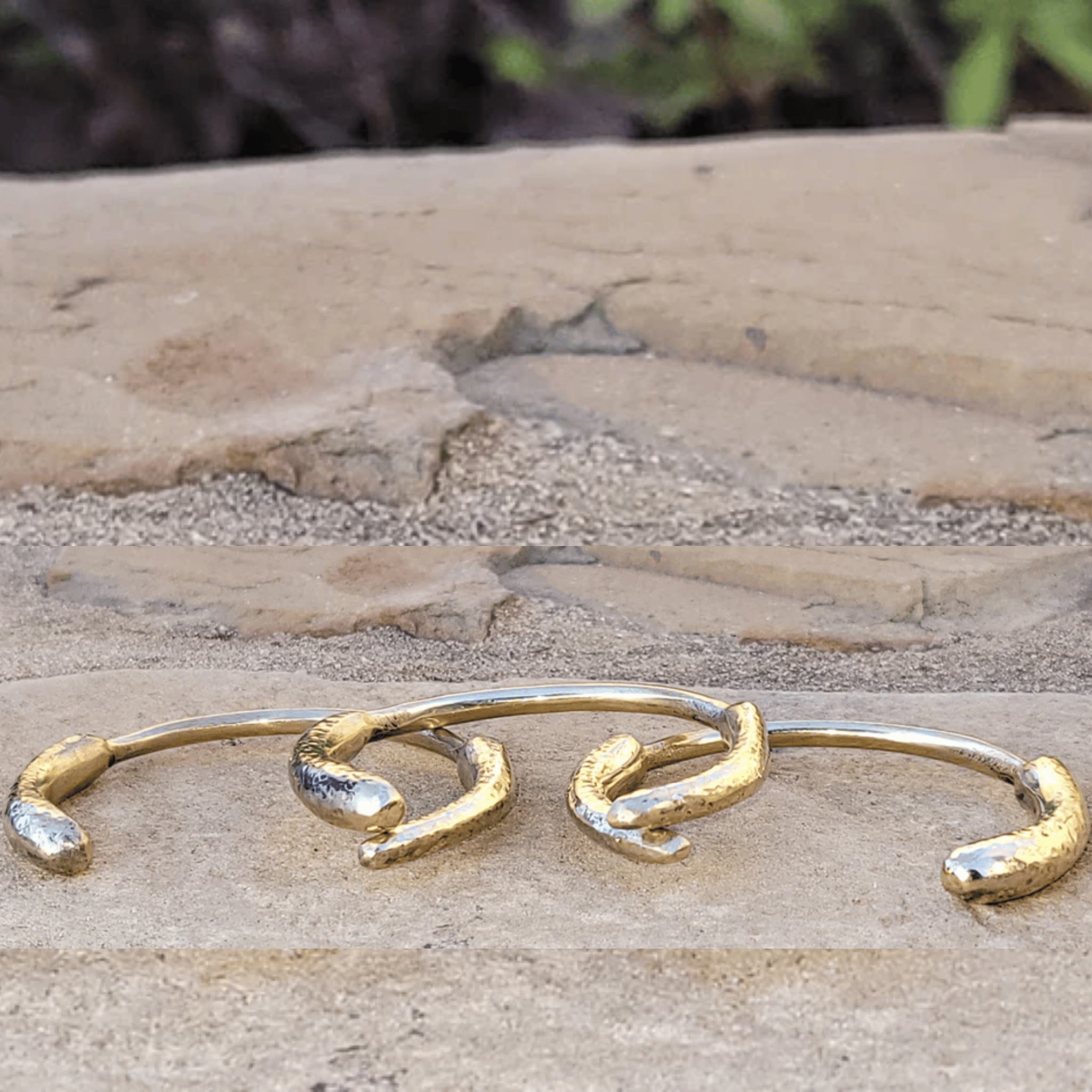 A pair of gold-toned spiral cuff earrings with textured, organic ends, displayed on a natural stone surface. Shop Kamawe