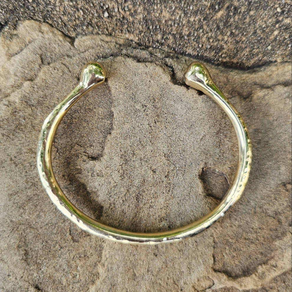 An image of gold-color Chunky hammered brass bracelet with bold pivot detail. Shop Kamawe