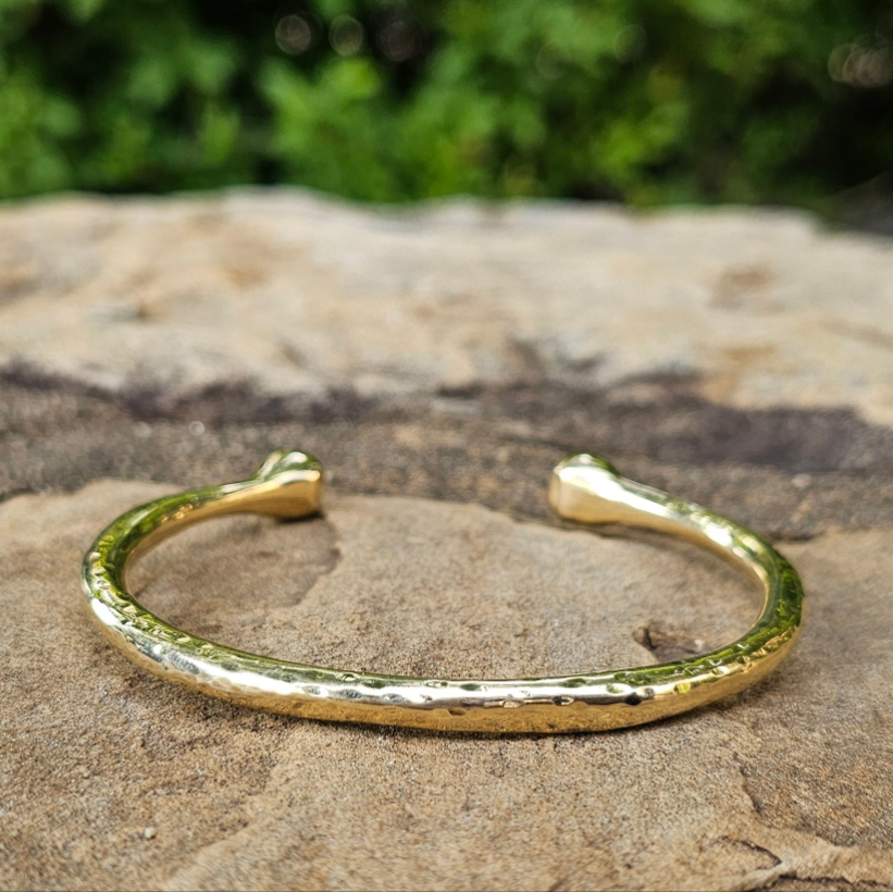 An image of gold-color Chunky hammered brass bracelet with bold pivot detail. Shop Kamawe