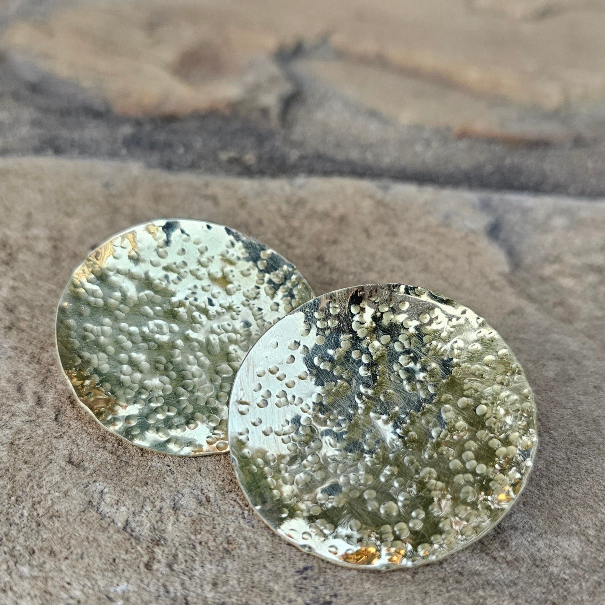 An image of gold-color Oversized hammered brass discs with organic texture. Shop Kamawe