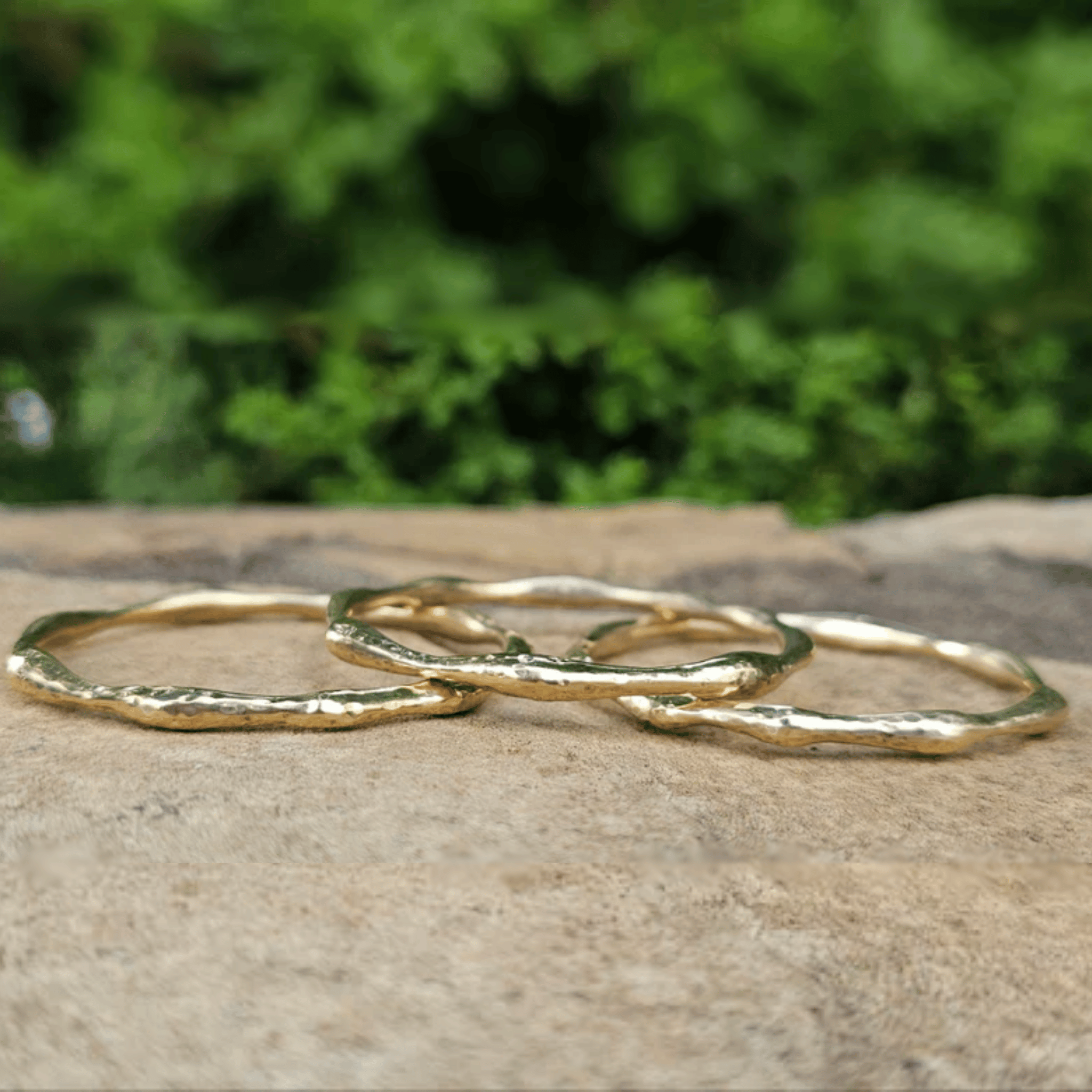 Three textured gold-color Bold hammered brass bangle with wave-like texture. Shop Kamawe