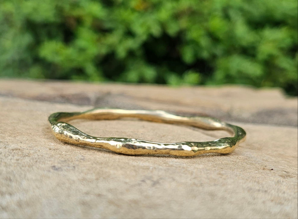 An image of gold-color Bold hammered brass bangle with wave-like texture. Shop Kamawe