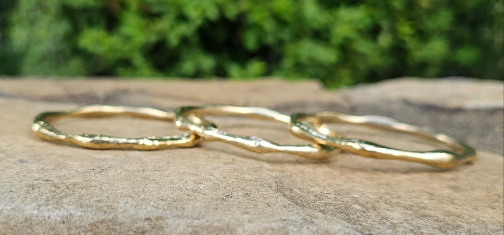 An image of gold-color Bold hammered brass bangle with wave-like texture. Shop Kamawe