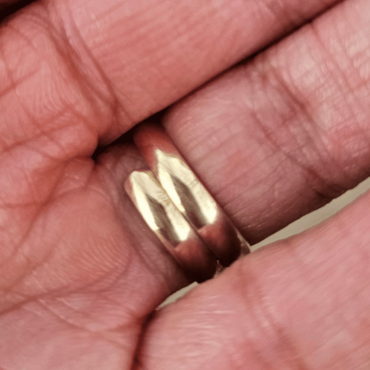 The inside of a gold ring with a large, oval white stone worn on a person's finger. Shop Kamawe