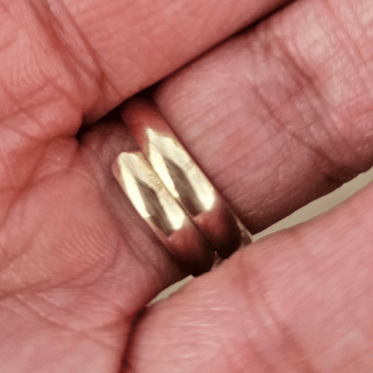 The back side of a gold ring with a large, polished white oval stone worn on a person's finger. Shop Kamawe