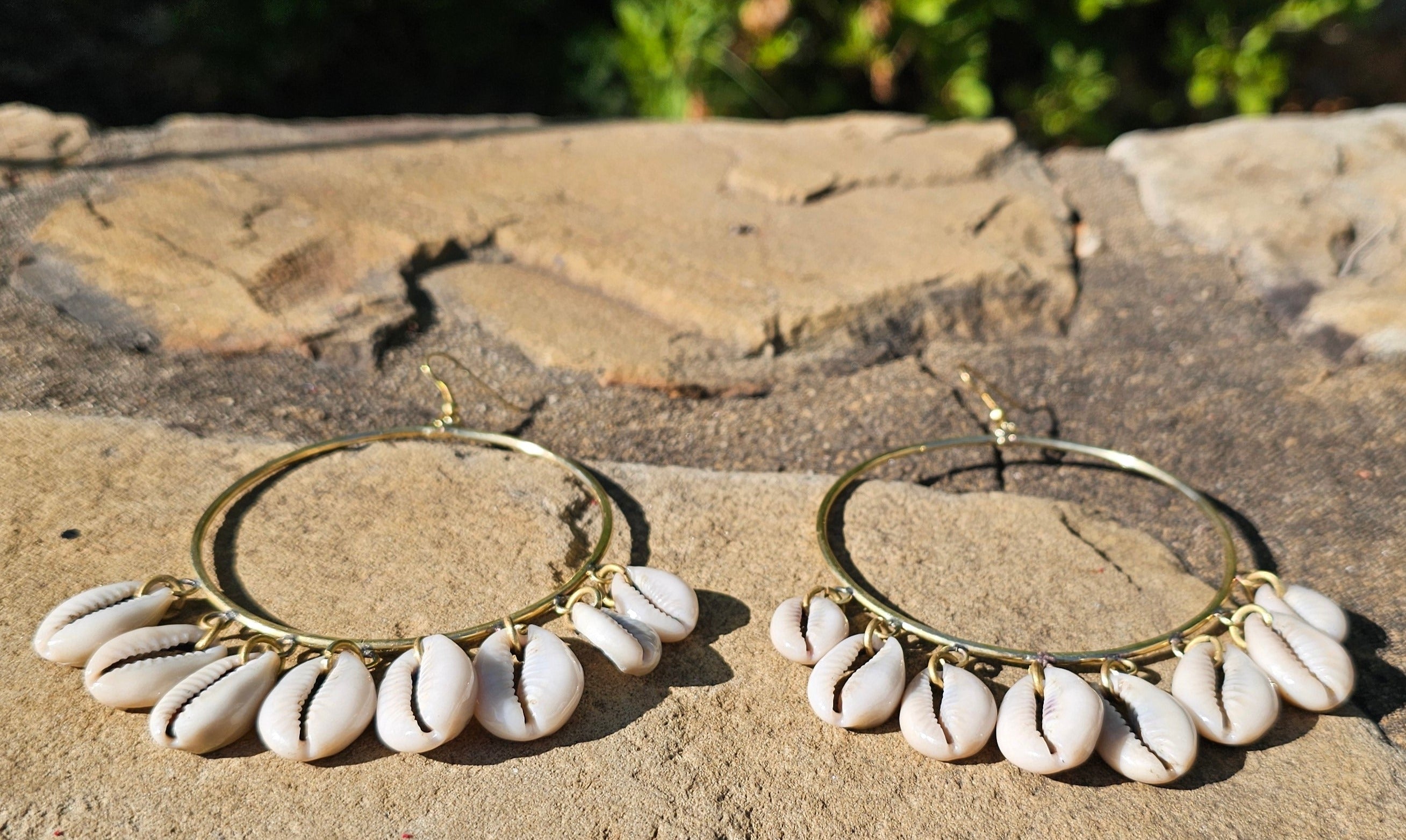 An image of gold & beige-color Mid-size hoops with layered falling cowrie shells. Shop Kamawe