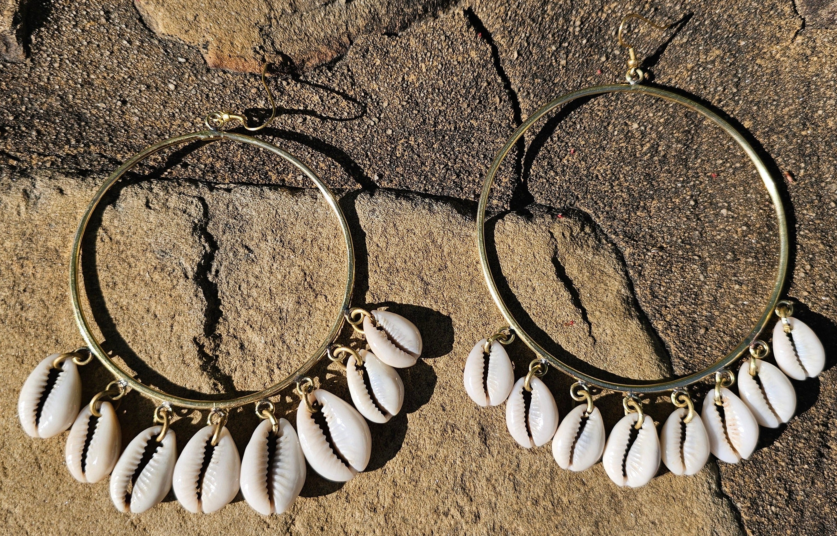 An image of gold & beige-color Mid-size hoops with layered falling cowrie shells. Shop Kamawe