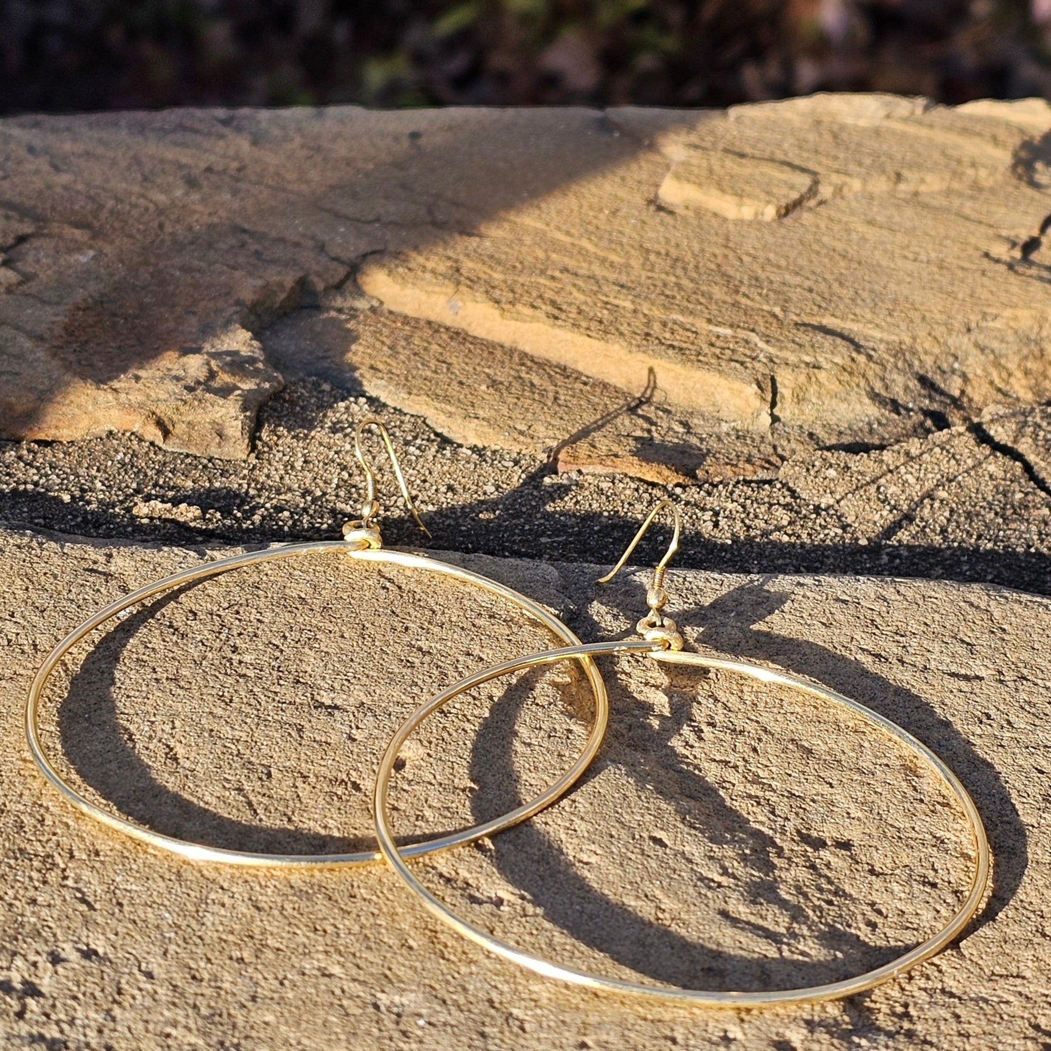 An image of gold-color Everyday mid-size polished brass hoops. Shop Kamawe