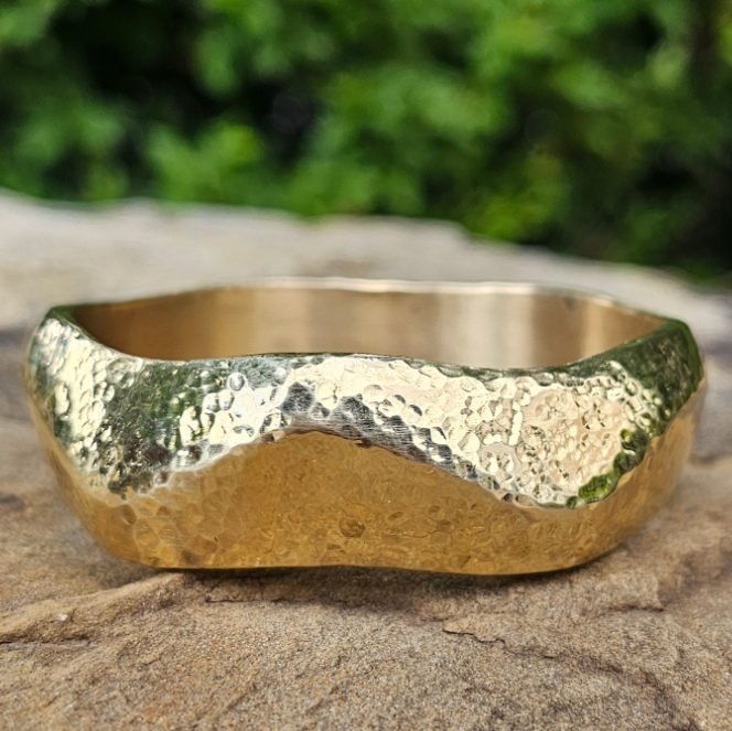 An image of gold-color Geometric faceted brass bangle that catches the light. Shop Kamawe