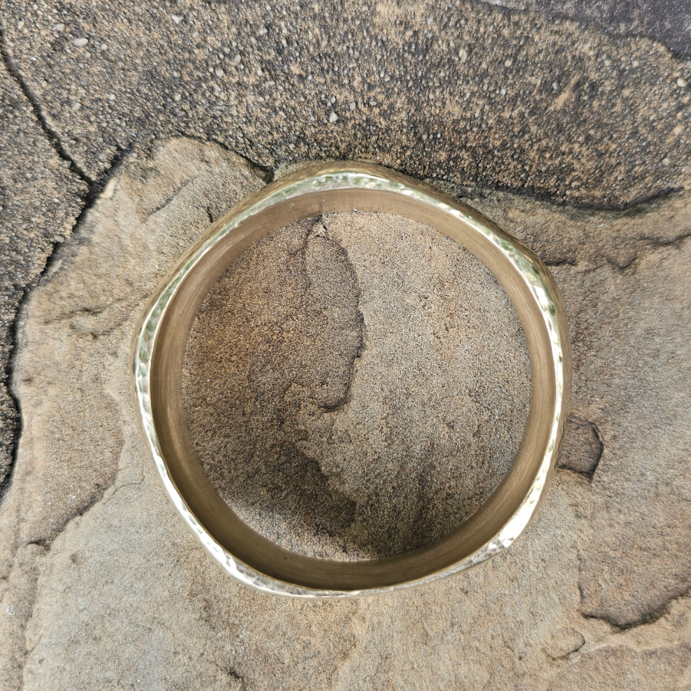 An image of gold-color Geometric faceted brass bangle that catches the light. Shop Kamawe