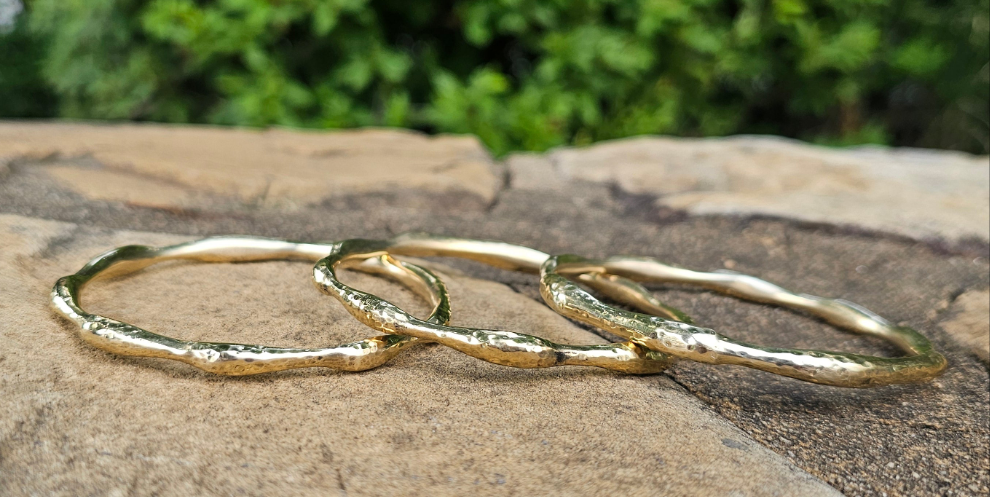 An image of gold-color Compact hammered brass bangle inspired by ocean ripples. Shop Kamawe