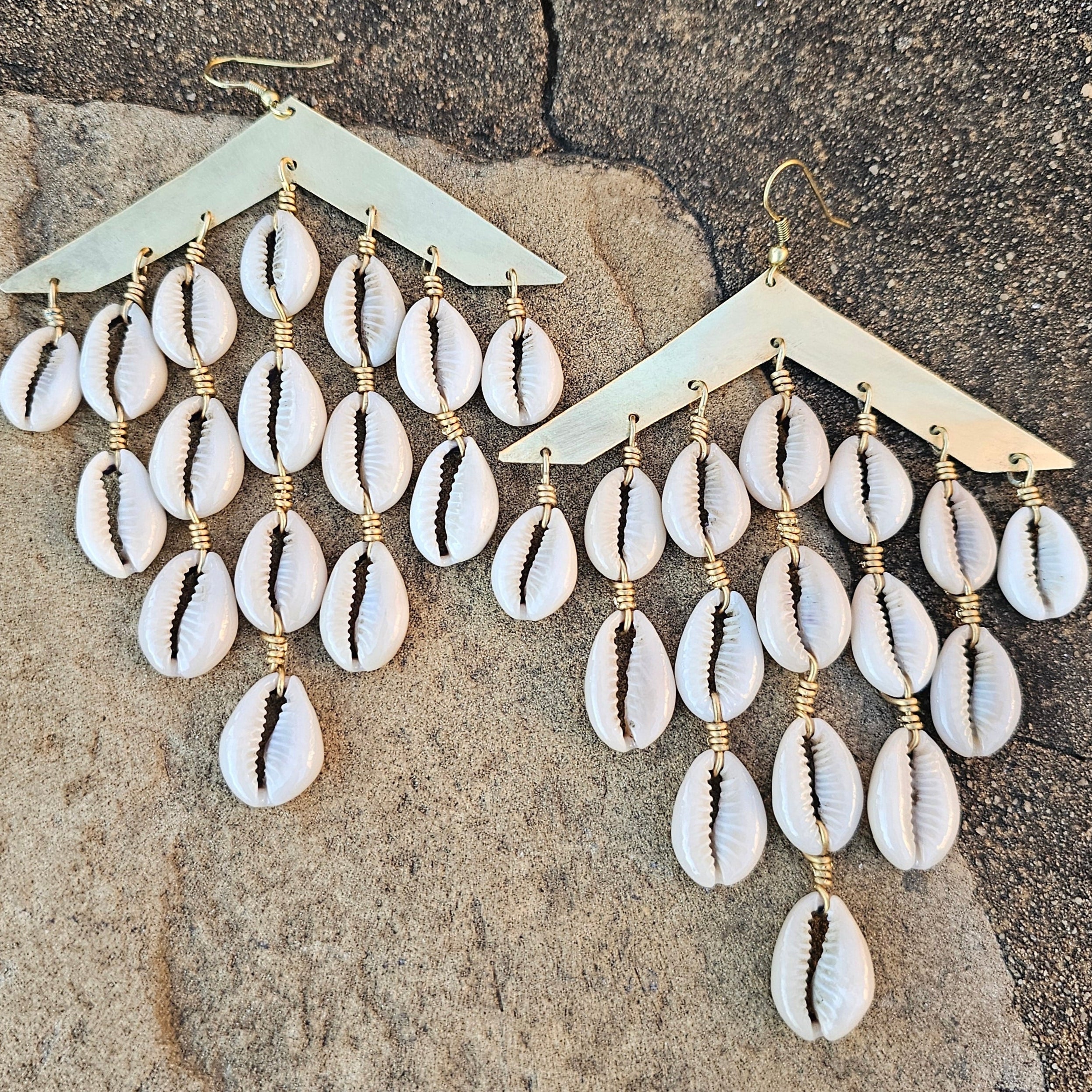 An image of gold & beige-color Cascading brass bars with layered cowrie shells. Shop Kamawe
