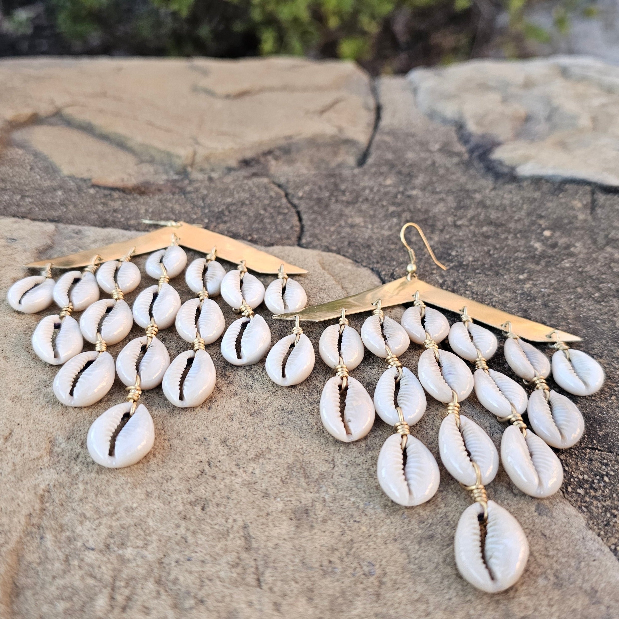 An image of gold & beige-color Cascading brass bars with layered cowrie shells. Shop Kamawe