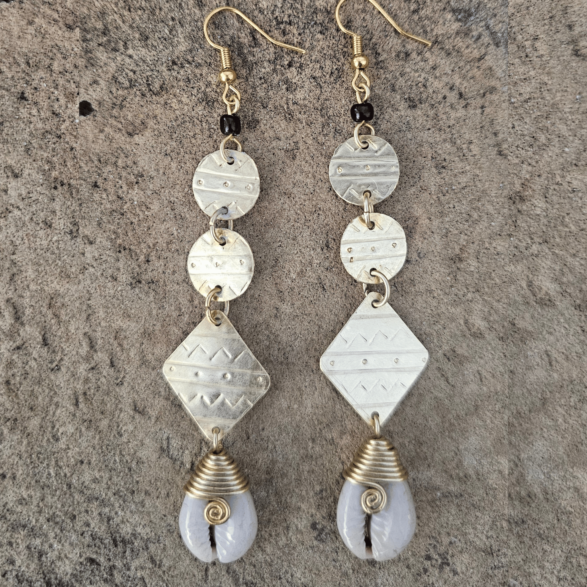 An image of gold & beige-color Statement brass drop earrings accented with authentic cowrie shells. Shop Kamawe