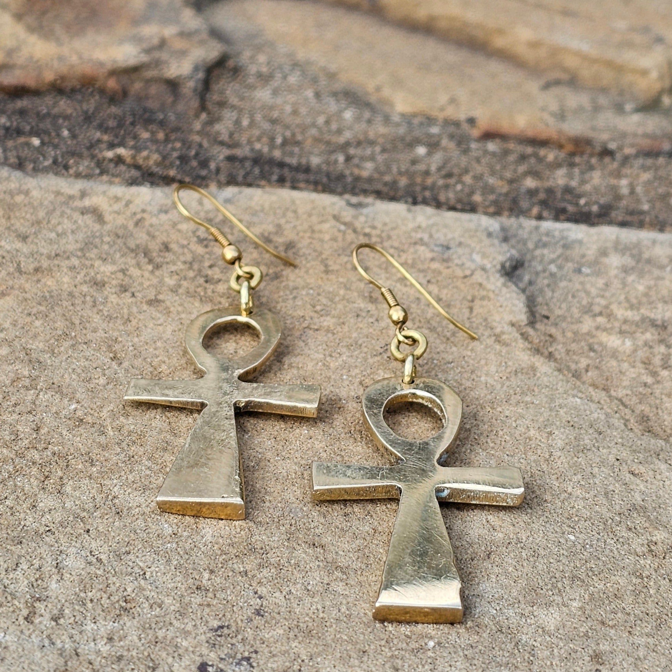 An image of gold-color Polished ankh symbols suspended in brass. Shop Kamawe