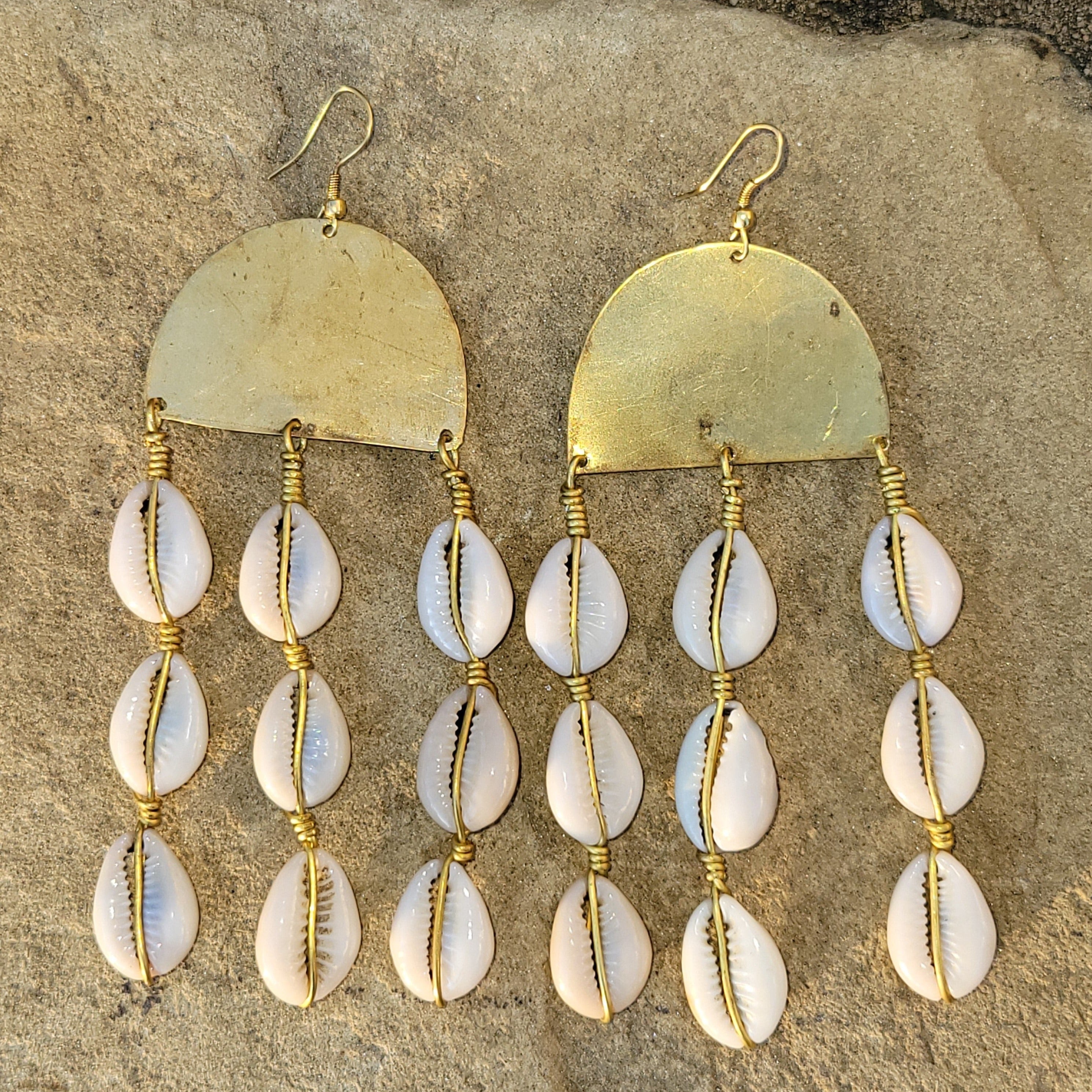 An image of gold & beige-color Polished brass with neatly layered hanging cowrie shells. Shop Kamawe