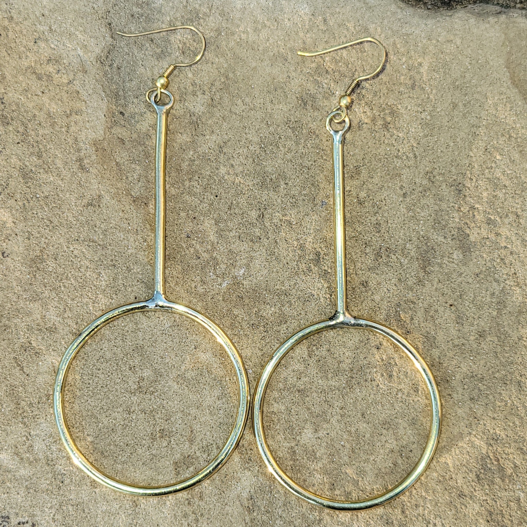 An image of gold-color Long, narrow hoops that stretch the classic silhouette. Shop Kamawe