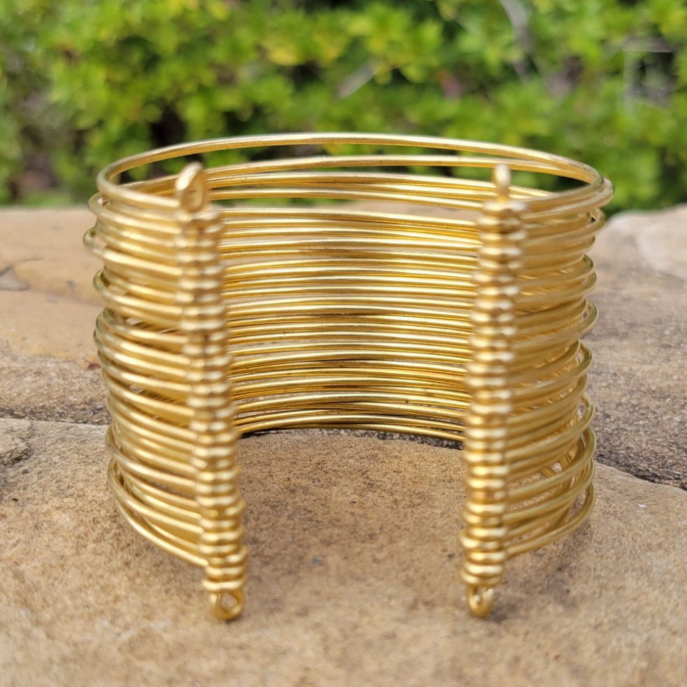 An image of Hand-wrapped wire detailing on a wide brass cuff. Shop Kamawe