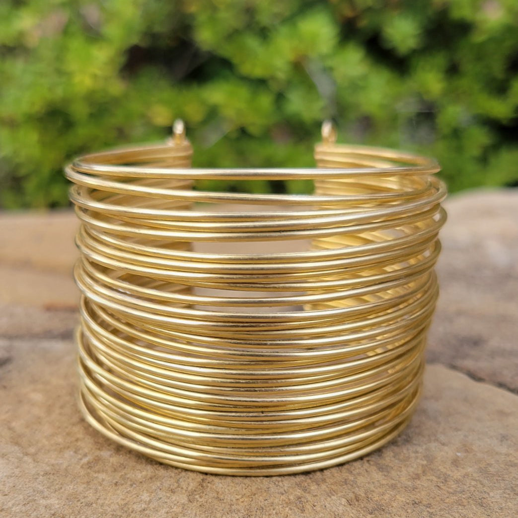 An image of Hand-wrapped wire detailing on a wide brass cuff. Shop Kamawe