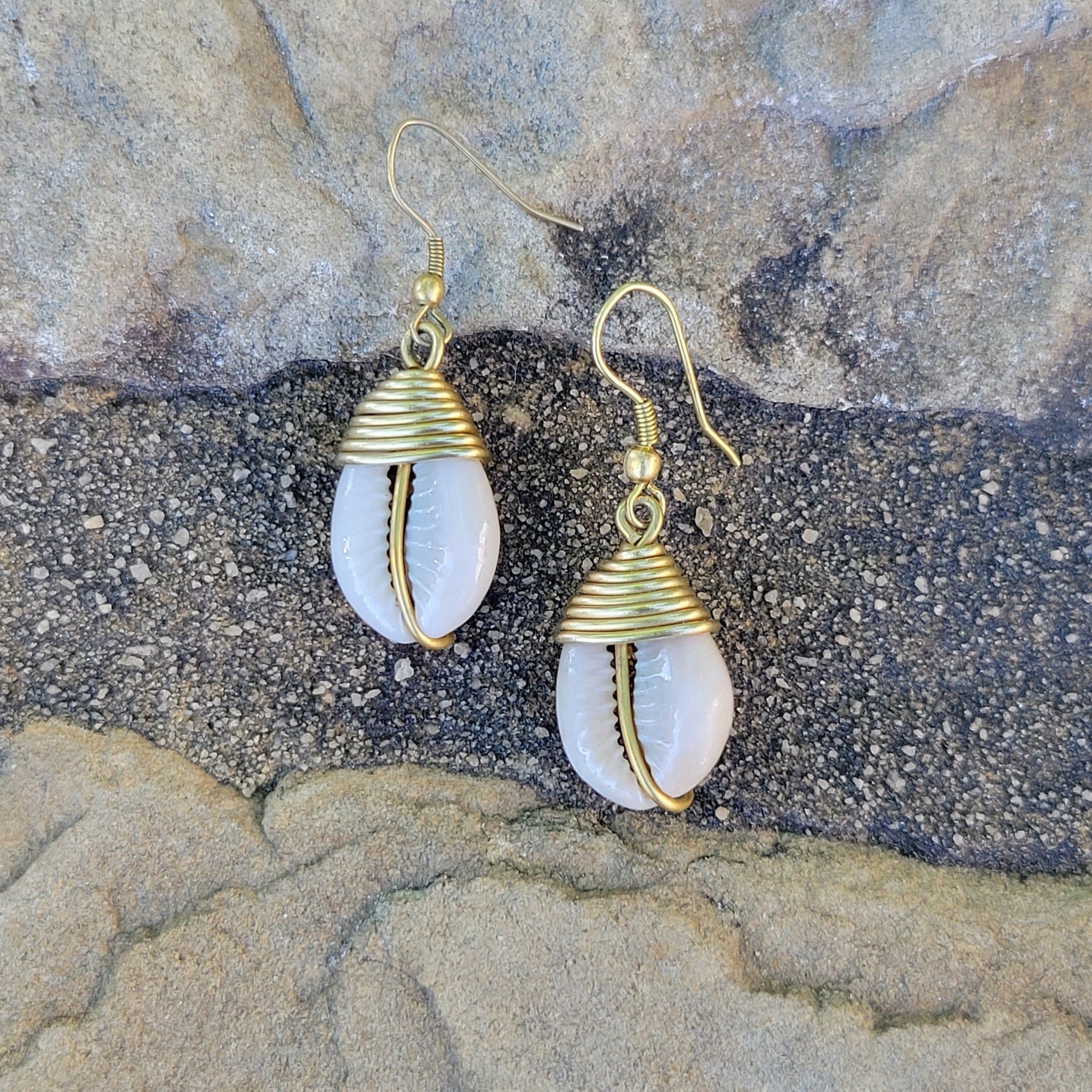 An image of gold & beige-color Simple brass drop finished with one cowrie. Shop Kamawe