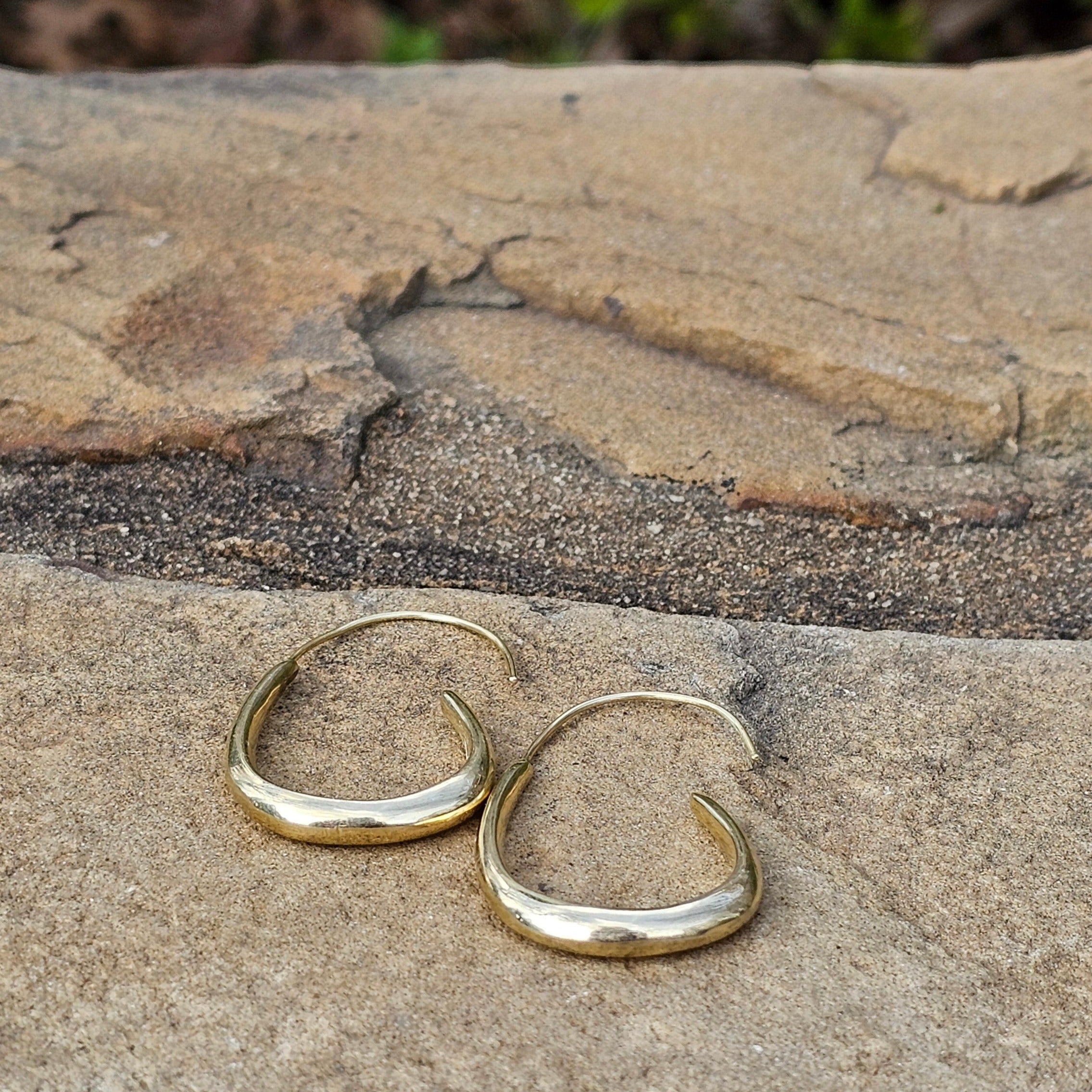 An image of gold-color One unbroken flowing brass line that arcs gently downward. Shop Kamawe