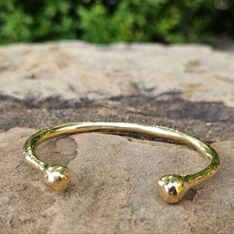 An image of gold-color Chunky hammered brass bracelet with bold pivot detail. Shop Kamawe