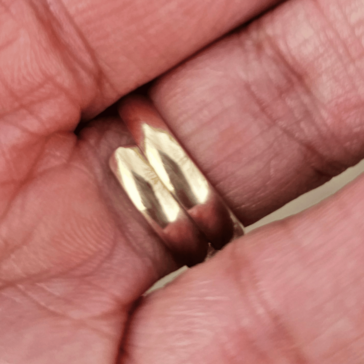The inside of a close-up of a silver ring with a large, smooth, oval white stone set on a finger. Shop Kamawe