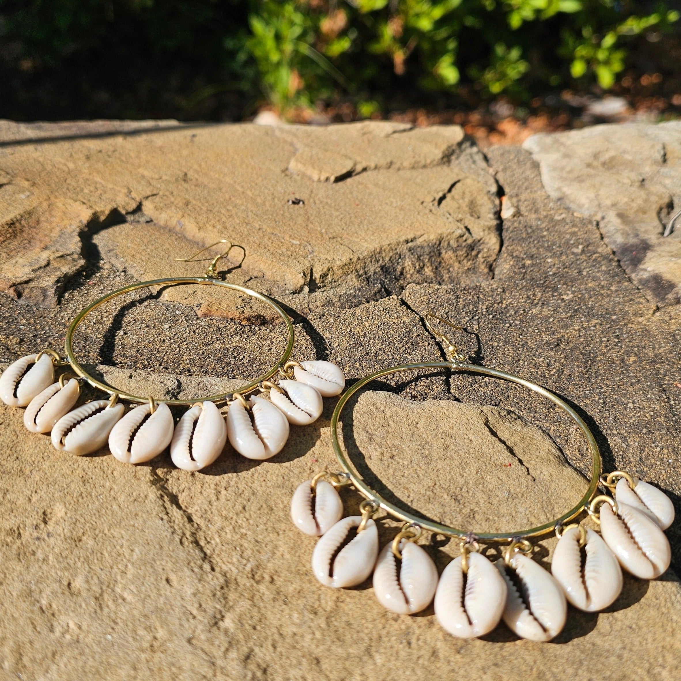 An image of gold & beige-color Mid-size hoops with layered falling cowrie shells. Shop Kamawe