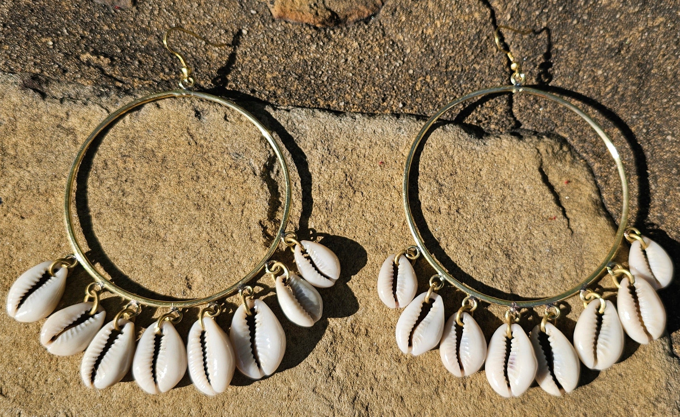 An image of gold & beige-color Mid-size hoops with layered falling cowrie shells. Shop Kamawe