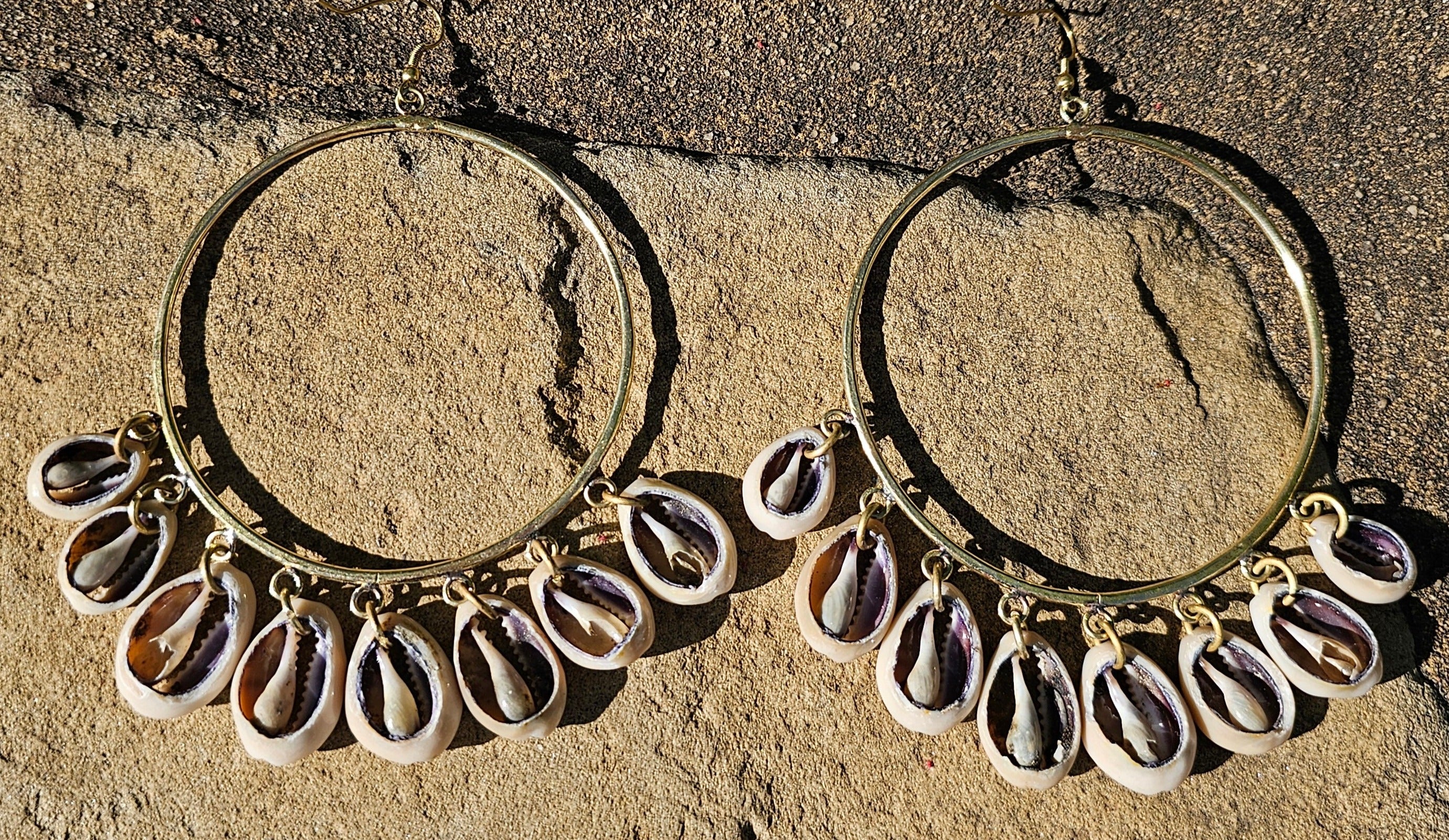 An image of gold & beige-color Mid-size hoops with layered falling cowrie shells. Shop Kamawe