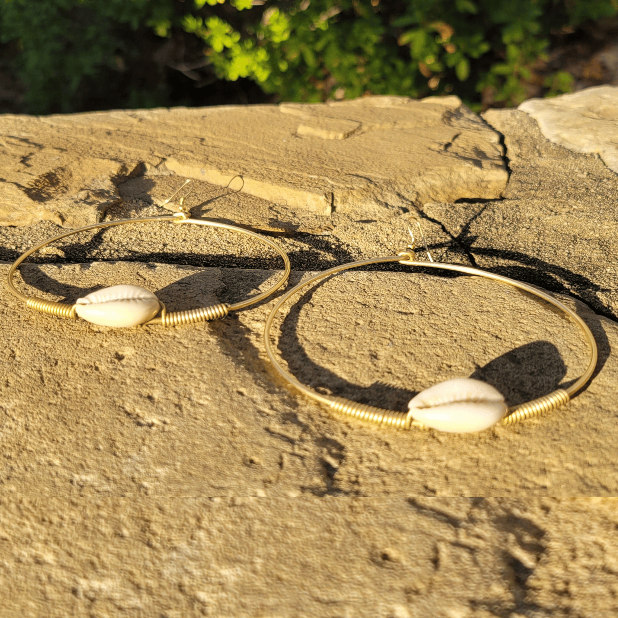 An image of gold & beige-color Small brass hoops carrying one cowrie each. Shop Kamawe