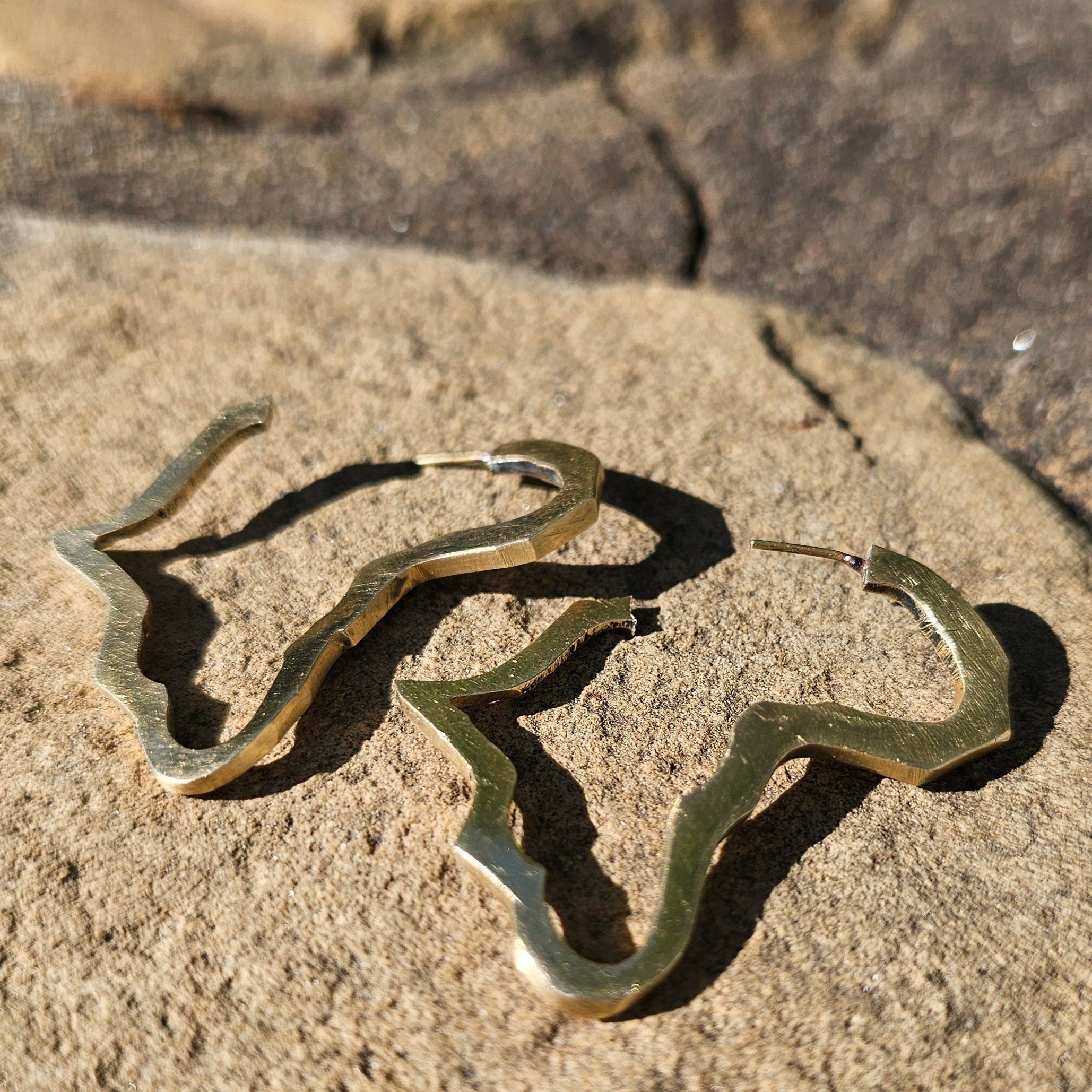 An image of gold-color Minimal open map silhouette in polished brass. Shop Kamawe