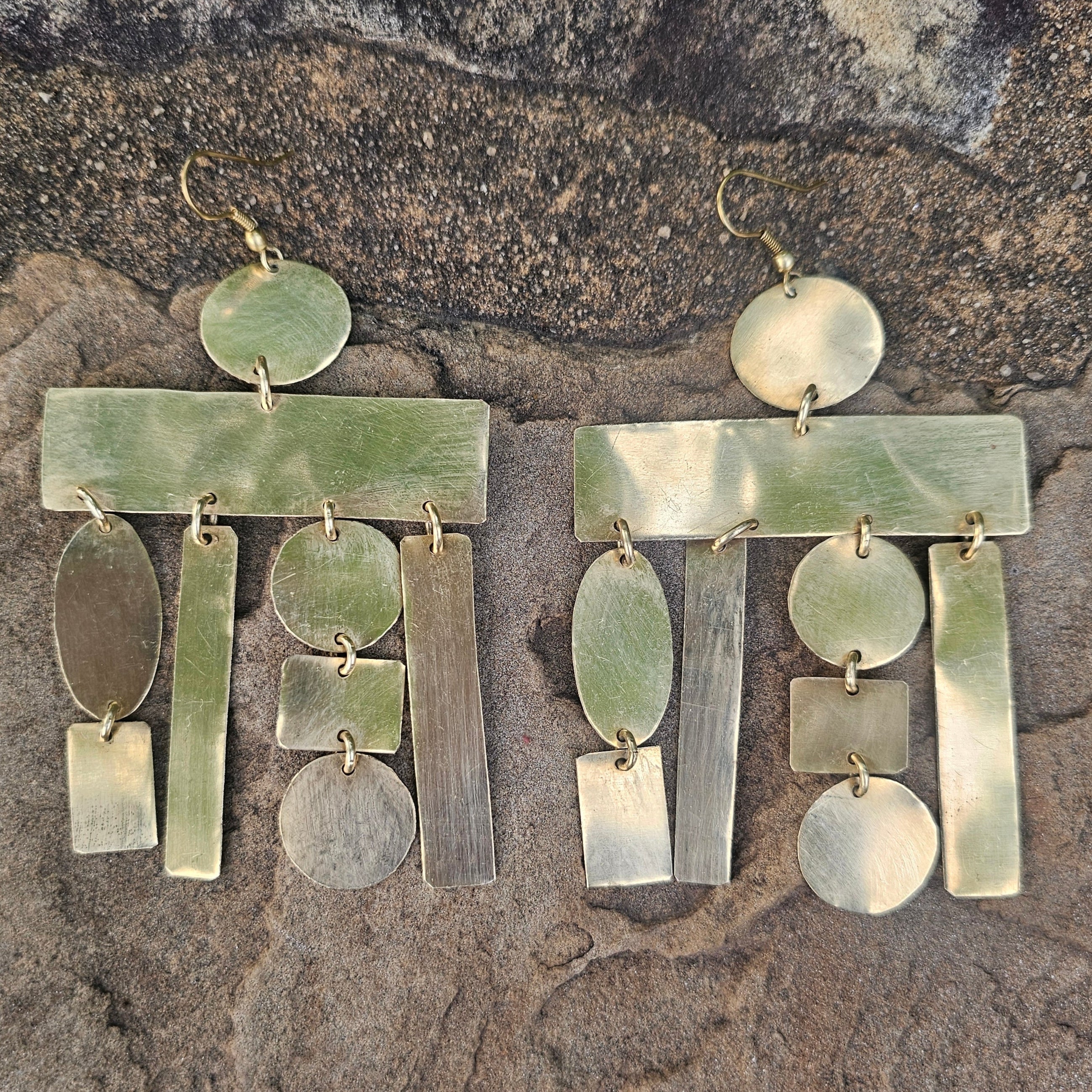 Pair of brass earrings on a stone surface