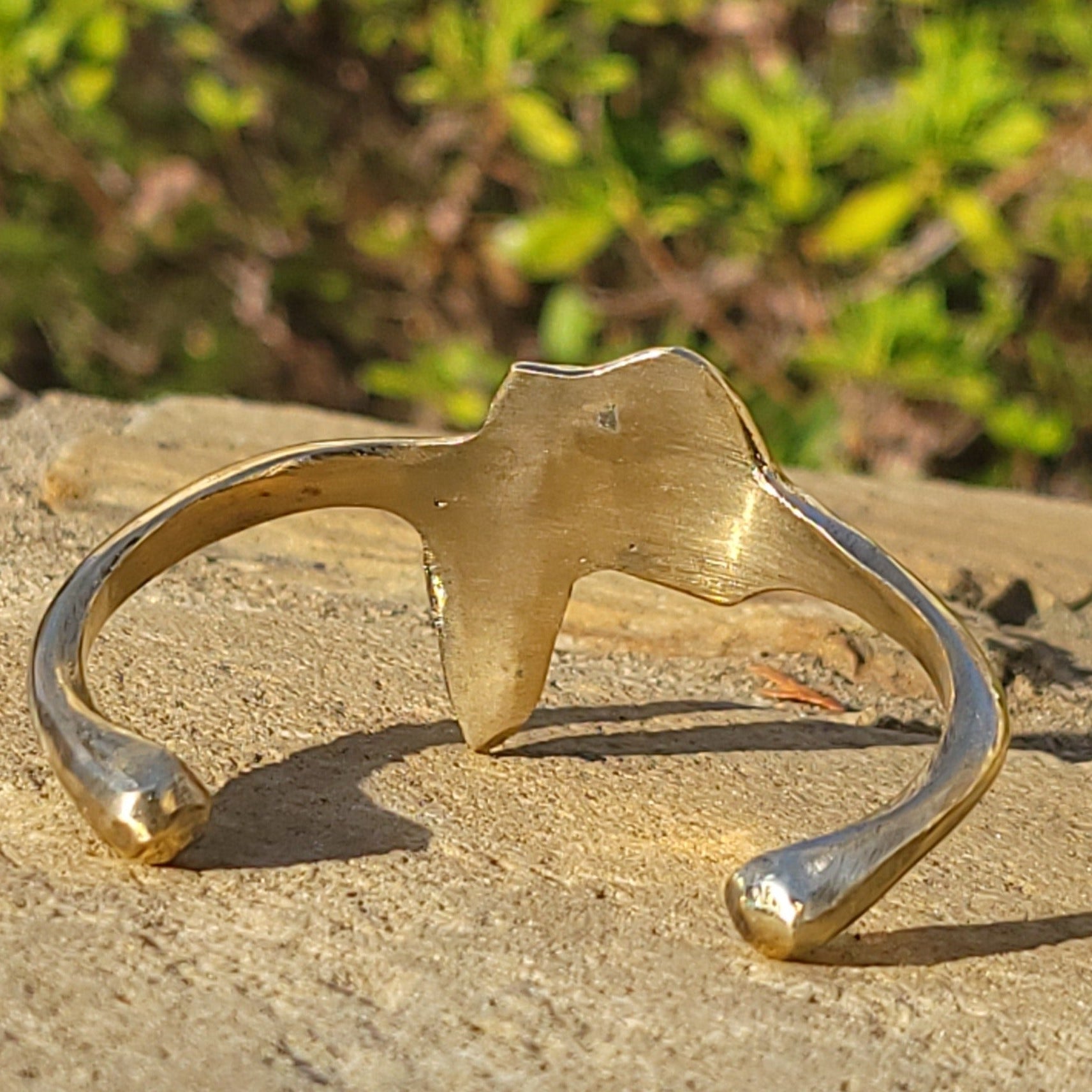 An image of gold-color Textured Motherland-map motif on an open brass cuff. Shop Kamawe