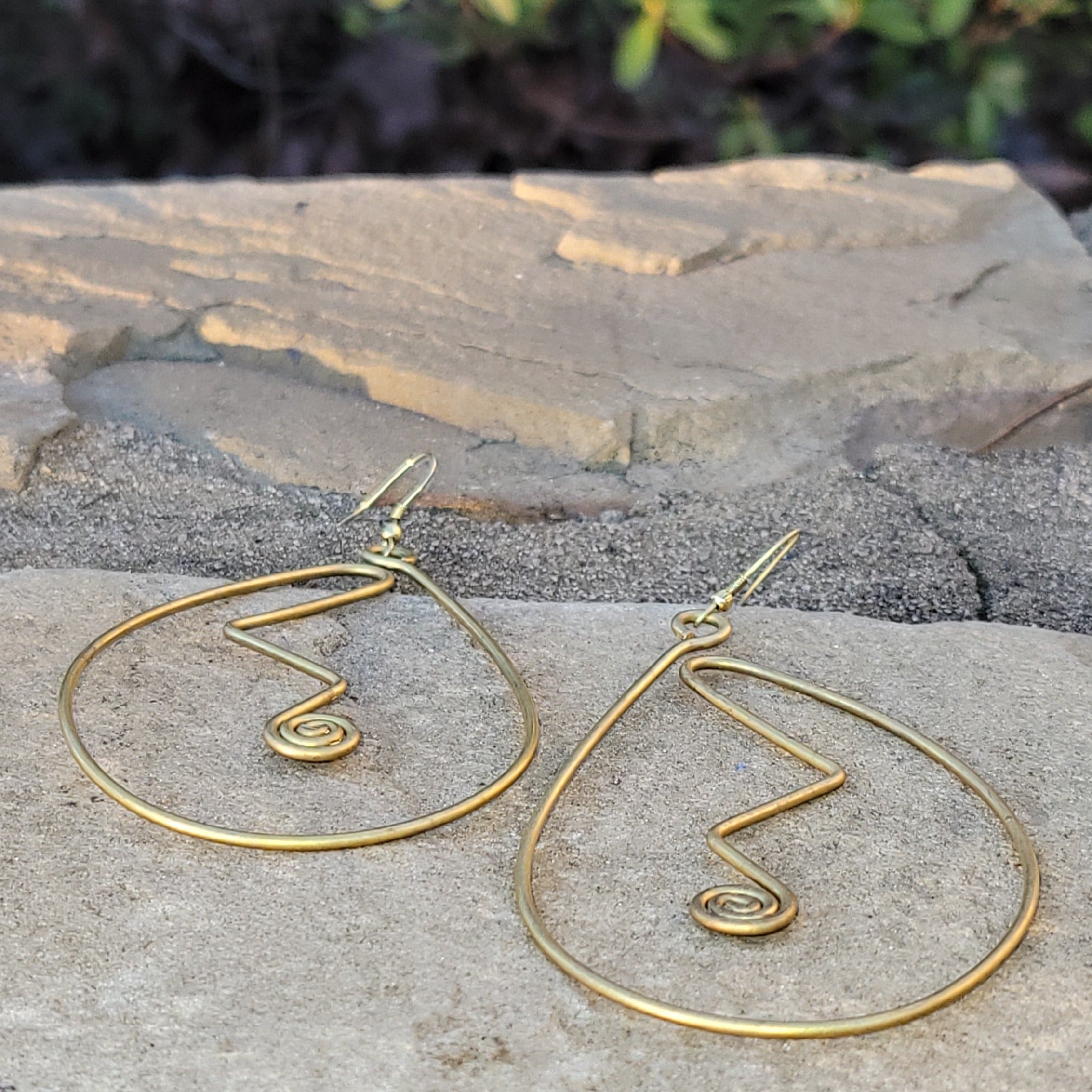 An image of gold-color Sweeping curved brass shapes that hug the line of the face. Shop Kamawe