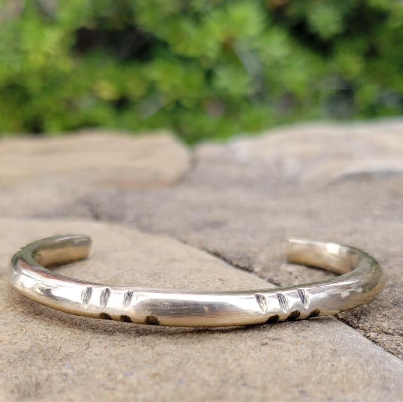 An image of Clean brass cuff defined by a central recessed line. Shop Kamawe