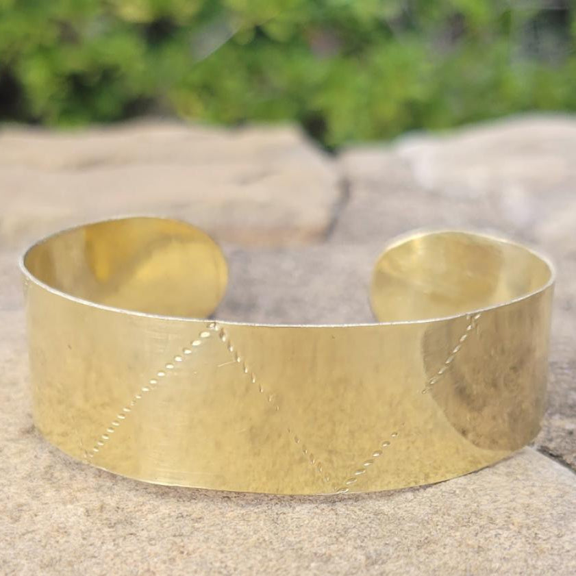 An image of gold-color Deep stamped patterns pressed into a solid brass cuff. Shop Kamawe