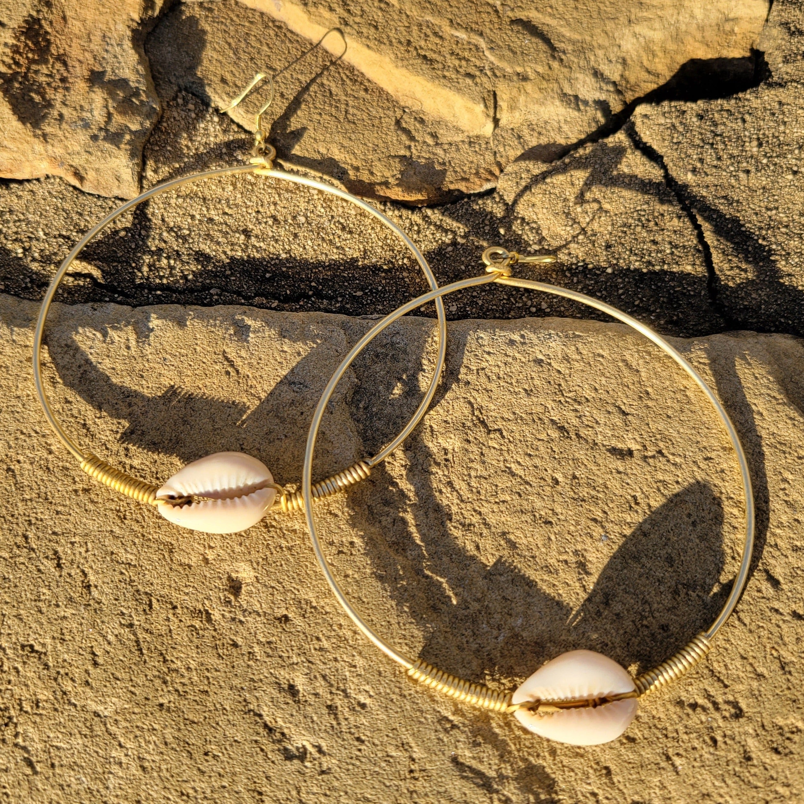 An image of gold & beige-color Small brass hoops carrying one cowrie each. Shop Kamawe